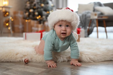 Cute baby in Santa hat crawling on floor. First Christmas Image of Cute baby in Santa hat crawling on floor. First Christmas