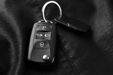 Modern car flip key with trinket on black leather, closeup Photo of Modern car flip key with trinket on black leather, closeup