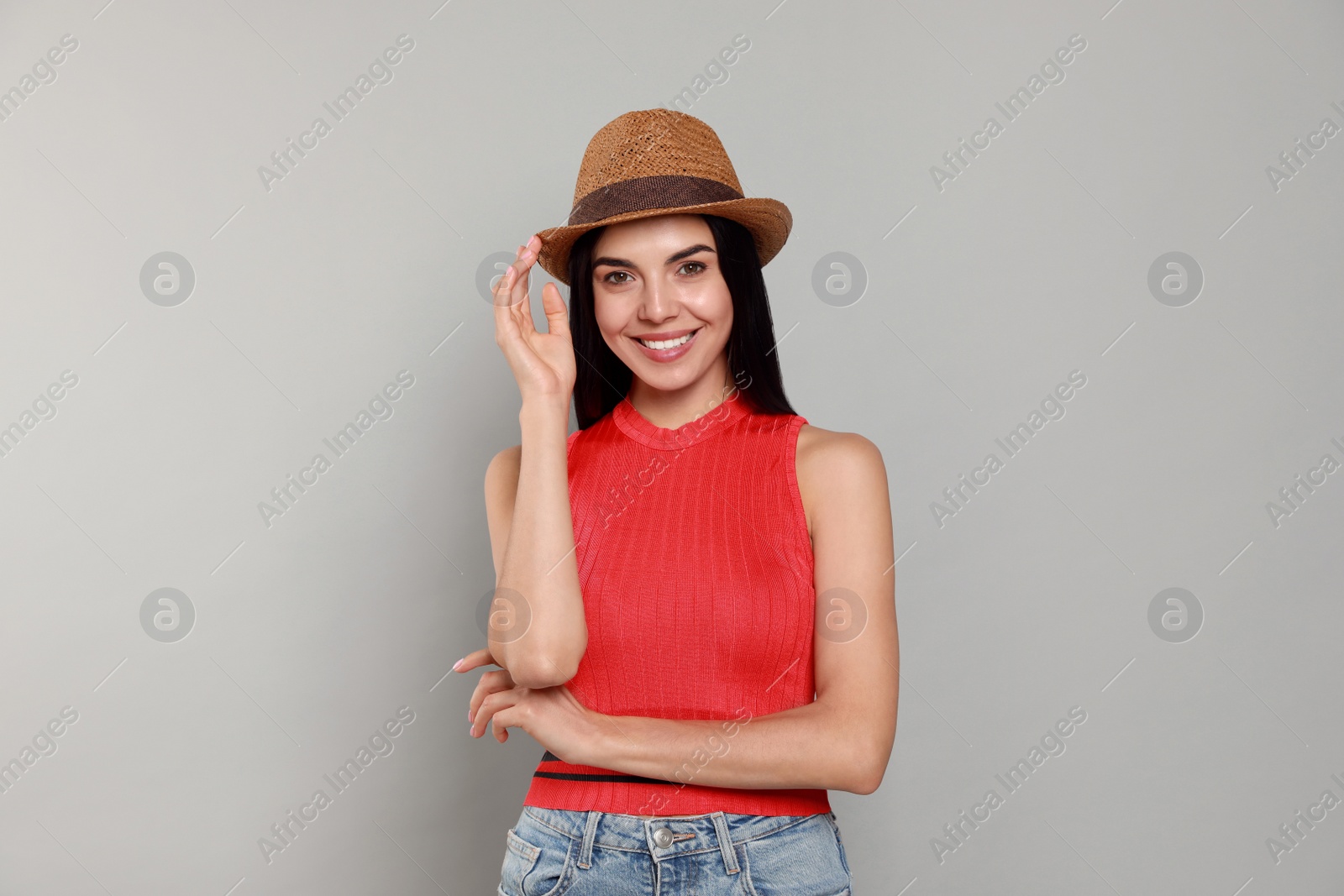 Beautiful young woman with straw hat on light grey background Photo of Beautiful young woman with straw hat on light grey background