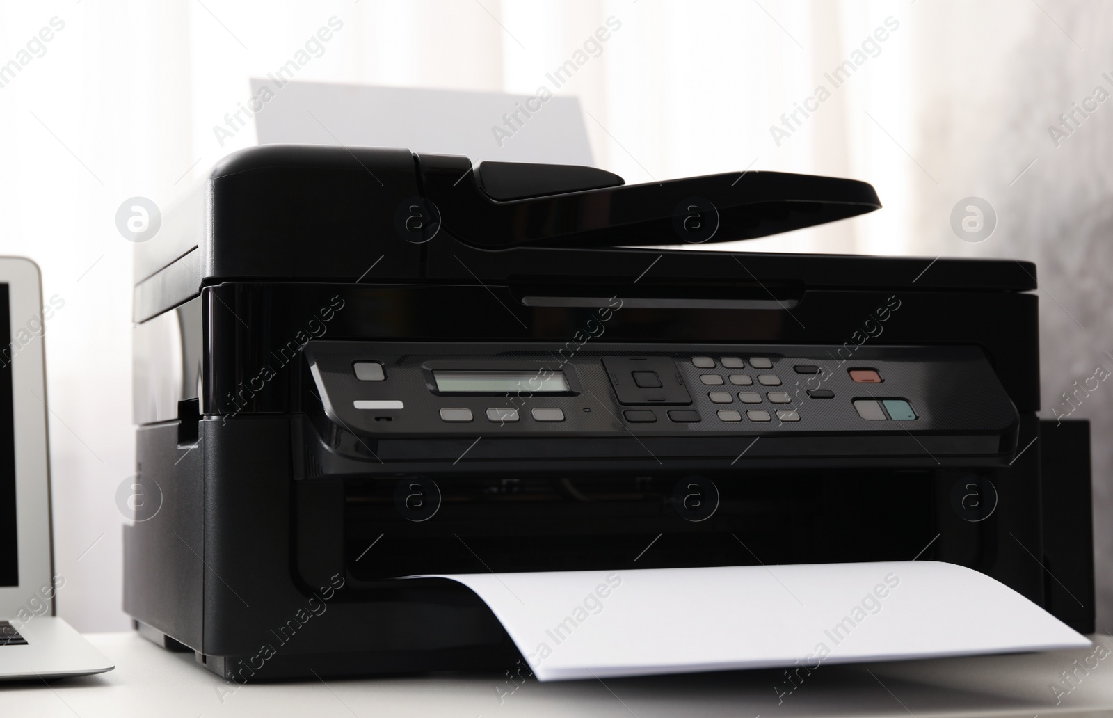 Modern printer with paper on white table Photo of Modern printer with paper on white table