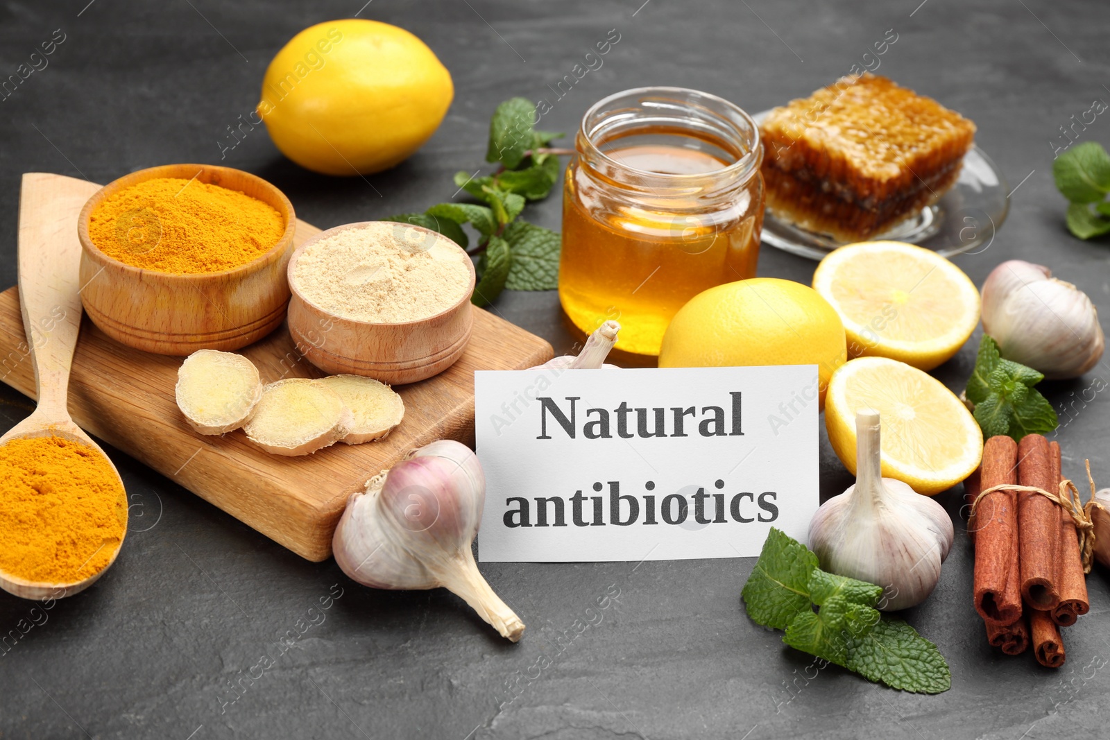 Different fresh products and card with phrase Natural Antibiotic on black table Photo of Different fresh products and card with phrase Natural Antibiotic on black table