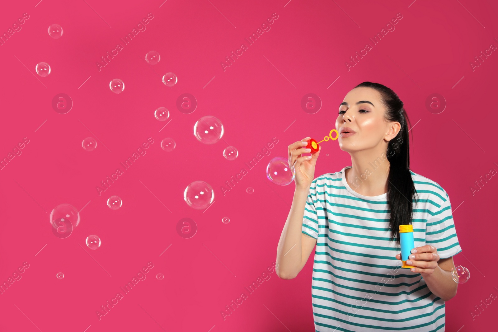 Young woman blowing soap bubbles on pink background, space for text Photo of Young woman blowing soap bubbles on pink background, space for text