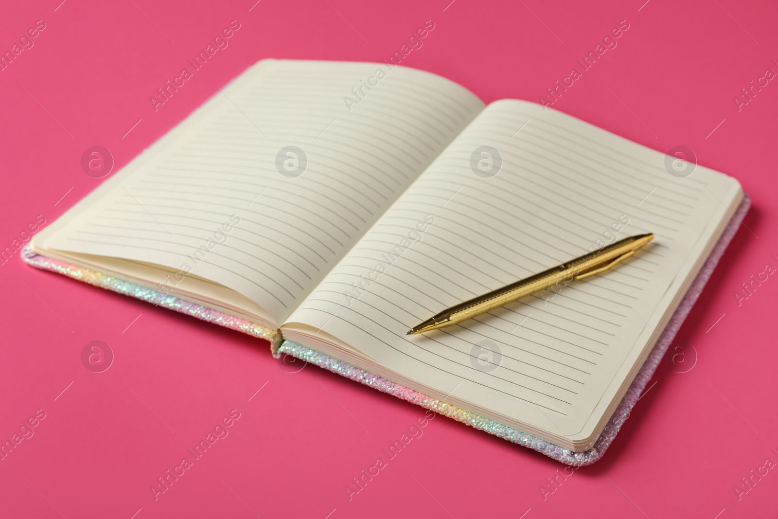 Stylish open notebook with blank sheets and pen on pink background Photo of Stylish open notebook with blank sheets and pen on pink background
