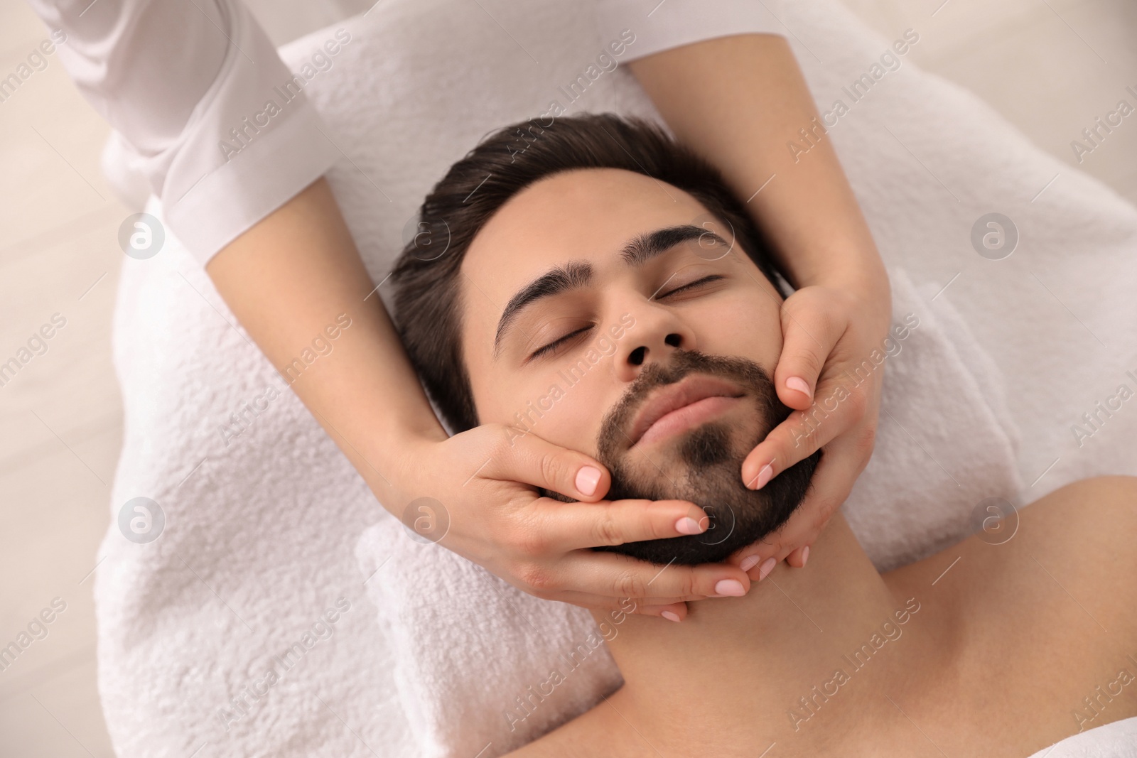 Young man receiving facial massage in beauty salon, above view Photo of Young man receiving facial massage in beauty salon, above view