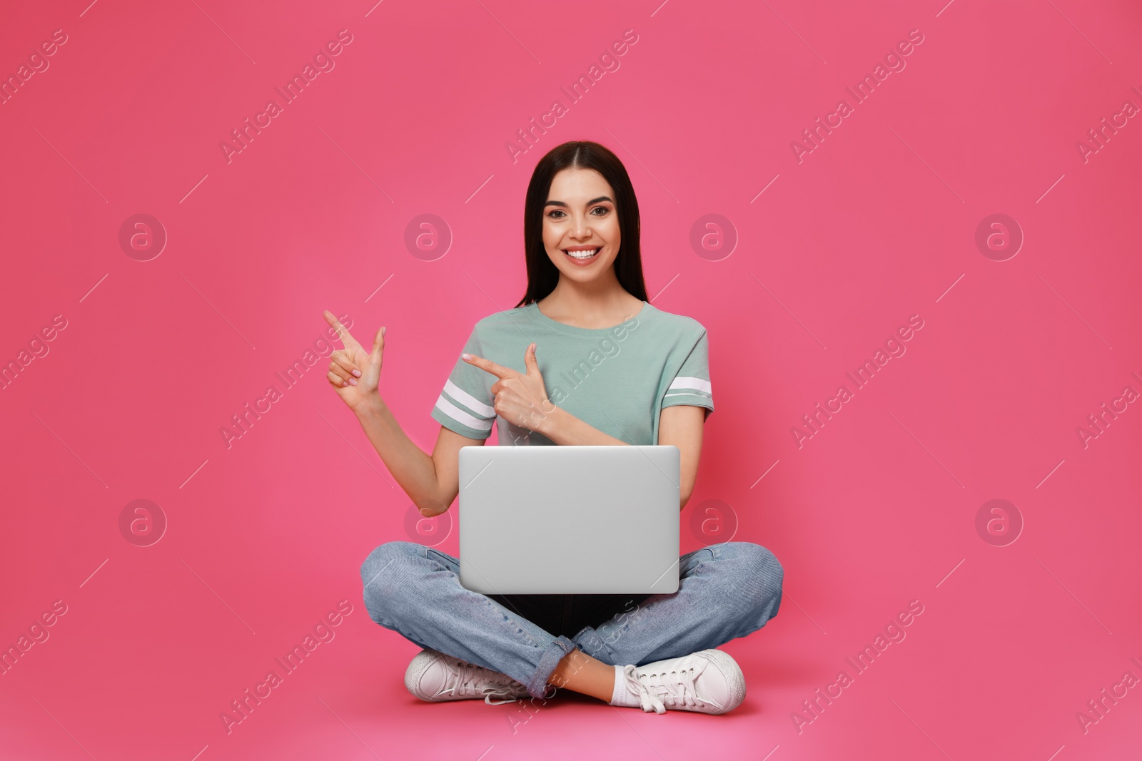 Young woman with modern laptop on pink background Photo of Young woman with modern laptop on pink background