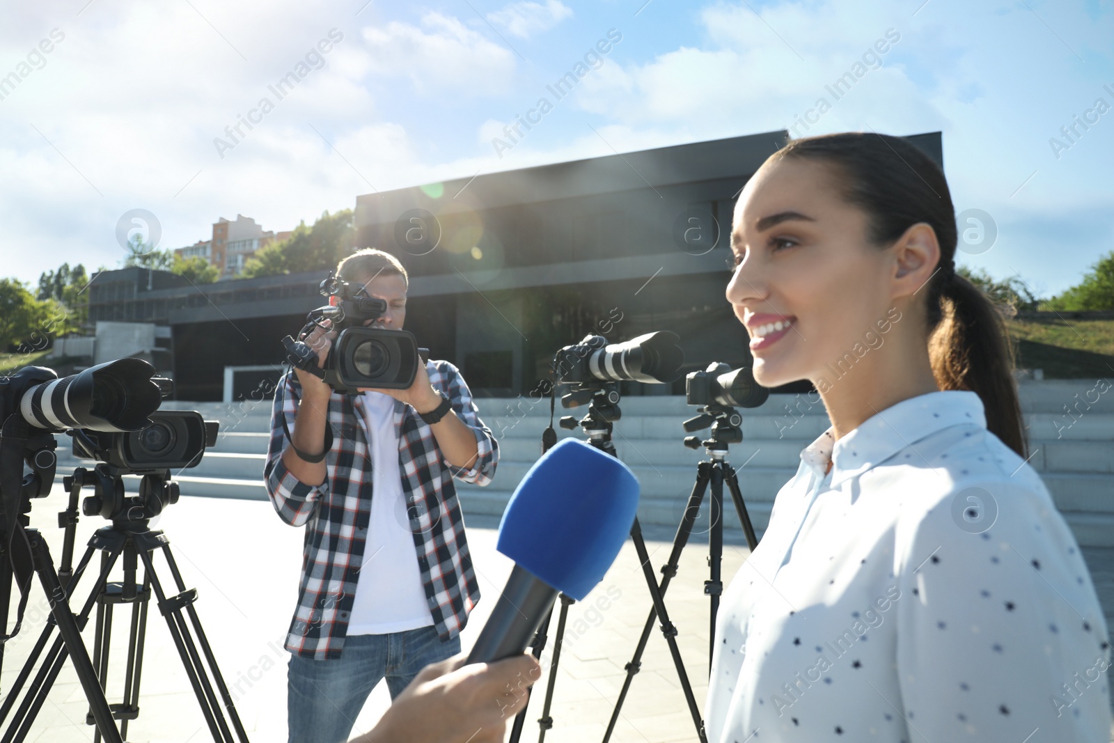 Professional journalist and operator with video camera taking interview outdoors Photo of Professional journalist and operator with video camera taking interview outdoors