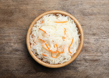Photo of Tasty fermented cabbage on wooden table, top view