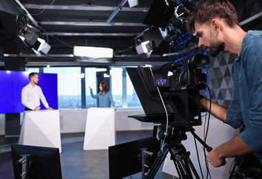Presenters and video camera operator working in studio. News broadcasting Photo of Presenters and video camera operator working in studio. News broadcasting