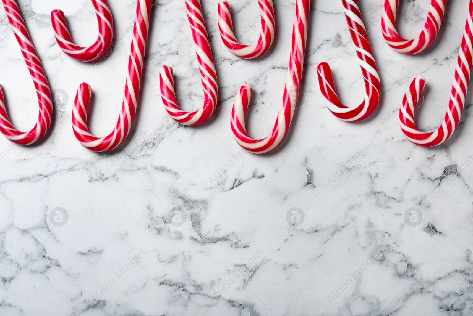 Sweet Christmas candy canes on white marble background, flat lay. Space for text Photo of Sweet Christmas candy canes on white marble background, flat lay. Space for text