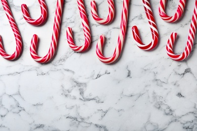 Sweet Christmas candy canes on white marble background, flat lay. Space for text Photo of Sweet Christmas candy canes on white marble background, flat lay. Space for text