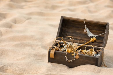 Open wooden treasure chest on sand, space for text Photo of Open wooden treasure chest on sand, space for text