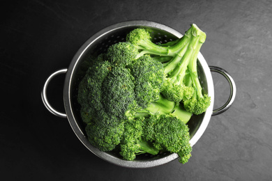 Fresh green broccoli in colander on black table, top view Photo of Fresh green broccoli in colander on black table, top view
