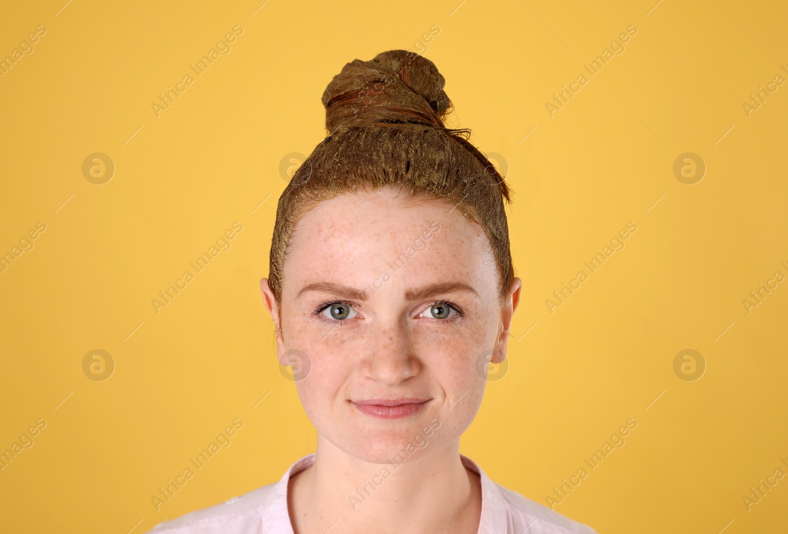 Young woman dyeing her hair with henna on yellow background Photo of Young woman dyeing her hair with henna on yellow background