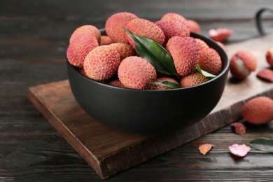 Fresh ripe lychee fruits in bowl on dark wooden table Photo of Fresh ripe lychee fruits in bowl on dark wooden table