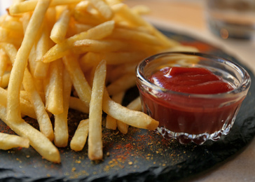Tasty French fries with red sauce served on table in cafe, closeup Photo of Tasty French fries with red sauce served on table in cafe, closeup