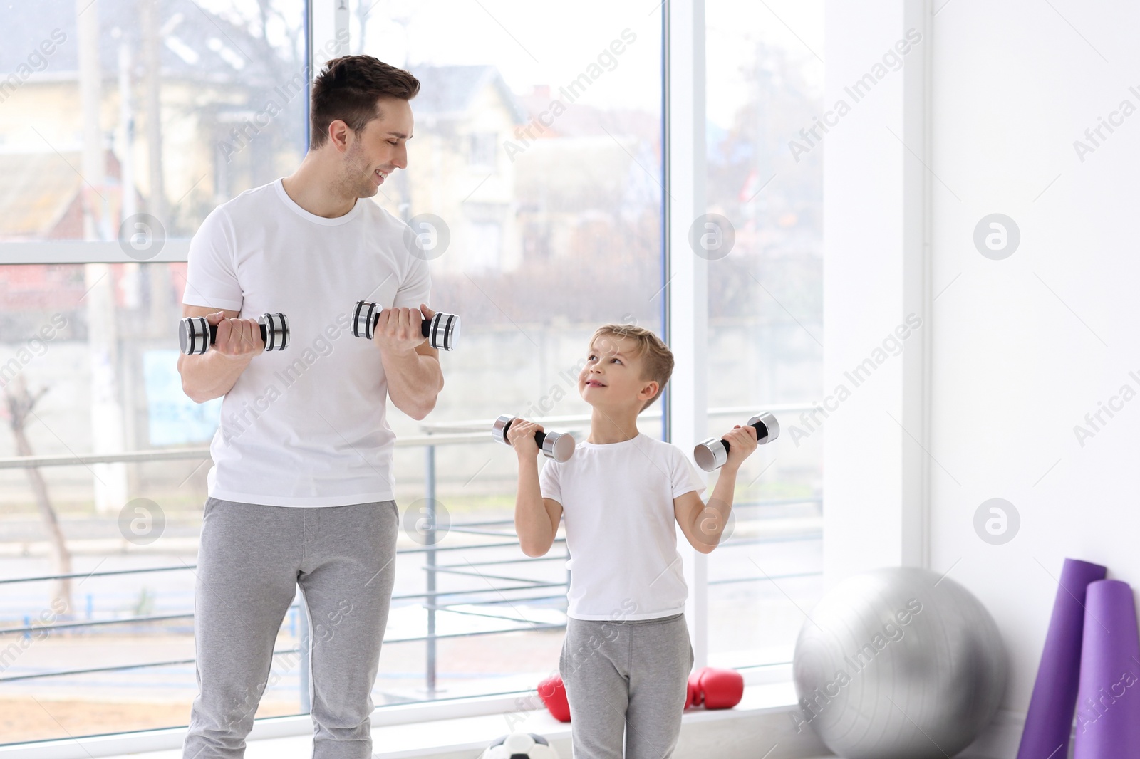 Dad and his son training with dumbbells in gym Photo of Dad and his son training with dumbbells in gym
