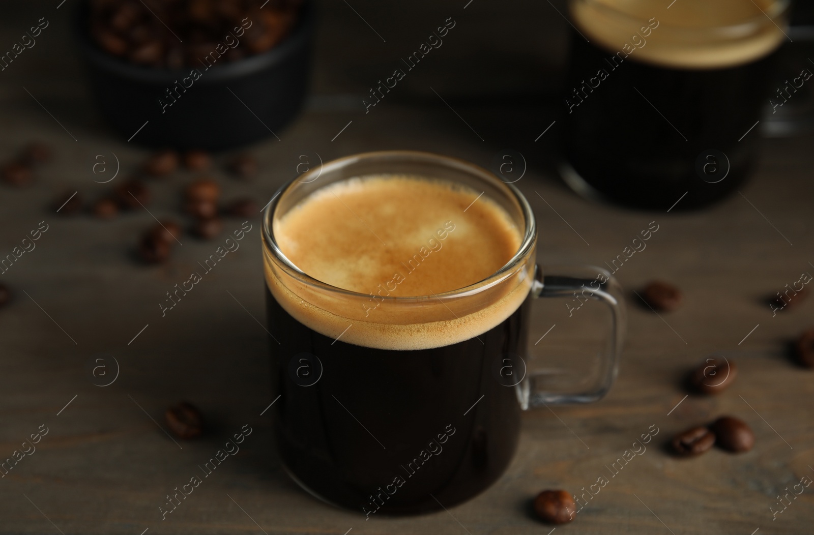 Cup of hot aromatic coffee and roasted beans on wooden table Photo of Cup of hot aromatic coffee and roasted beans on wooden table