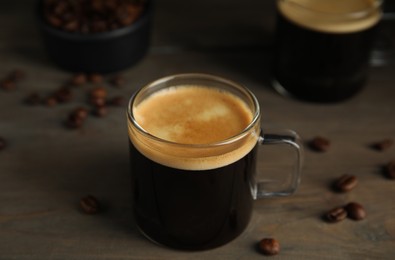 Cup of hot aromatic coffee and roasted beans on wooden table Photo of Cup of hot aromatic coffee and roasted beans on wooden table