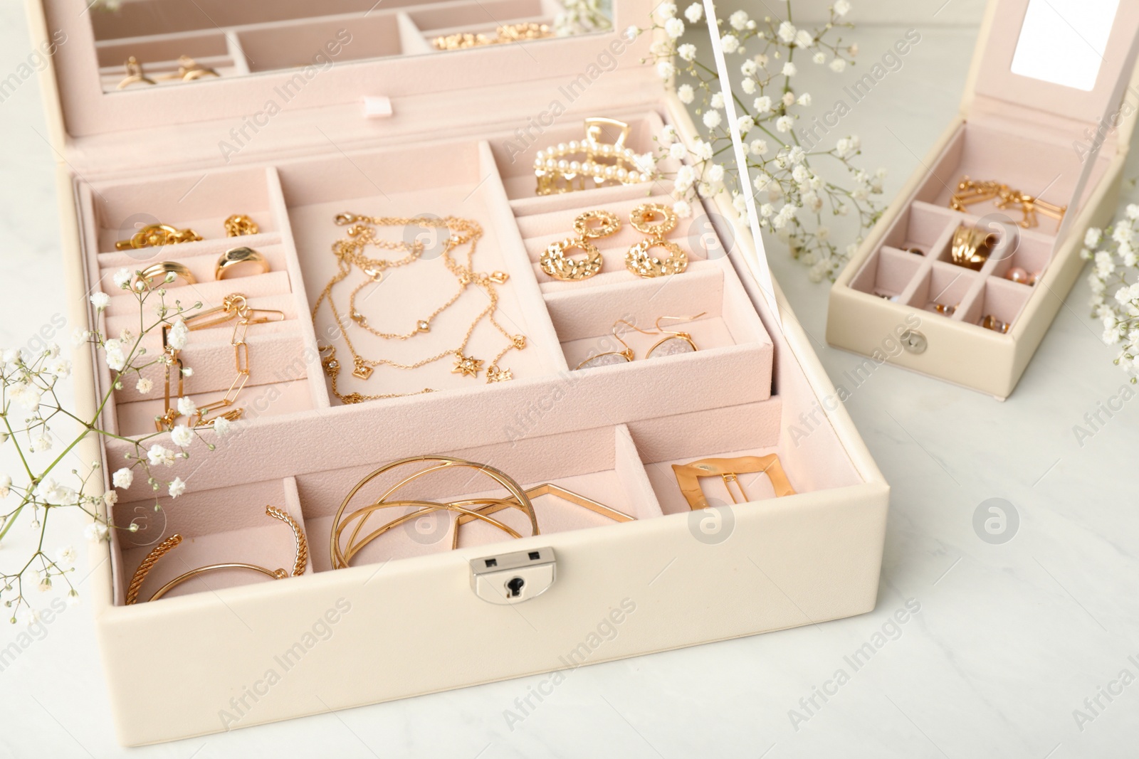 Jewelry boxes with different elegant bijouterie and flowers on white table Photo of Jewelry boxes with different elegant bijouterie and flowers on white table