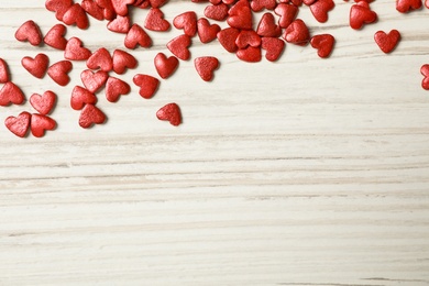 Bright heart shaped sprinkles on white wooden table, flat lay. Space for text Photo of Bright heart shaped sprinkles on white wooden table, flat lay. Space for text