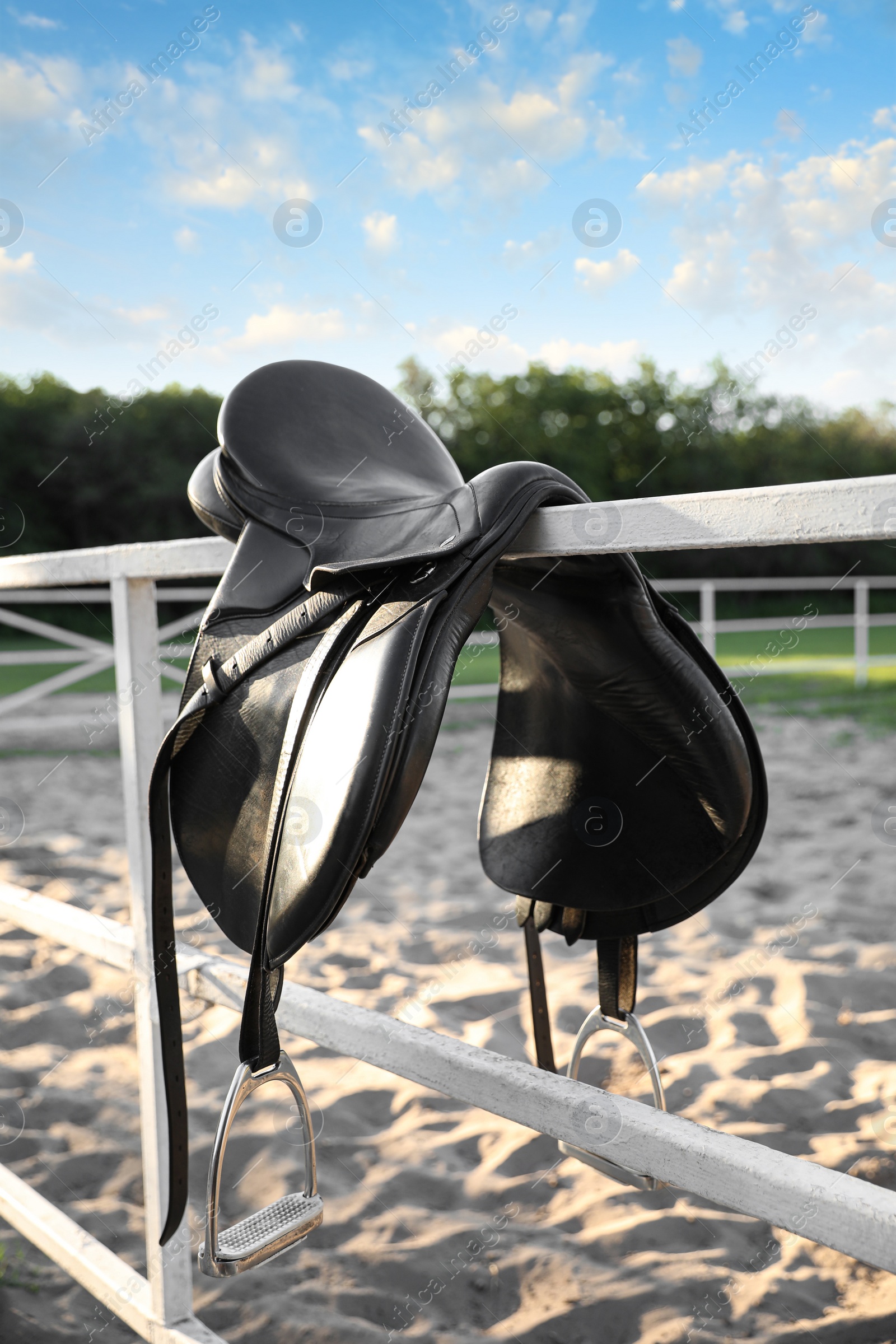 Leather horse saddle on wooden fence outdoors Photo of Leather horse saddle on wooden fence outdoors