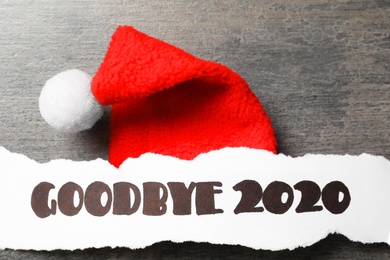 Paper sheet with text Goodbye 2020 and Santa hat on grey background, flat lay Photo of Paper sheet with text Goodbye 2020 and Santa hat on grey background, flat lay