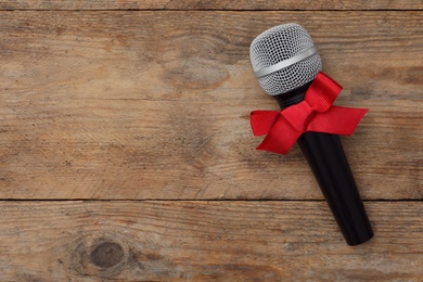 Top view of microphone with red bow on wooden table, space for text. Christmas music Photo of Top view of microphone with red bow on wooden table, space for text. Christmas music