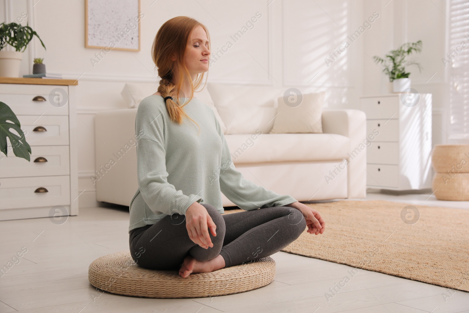 Woman meditating on wicker mat at home Photo of Woman meditating on wicker mat at home