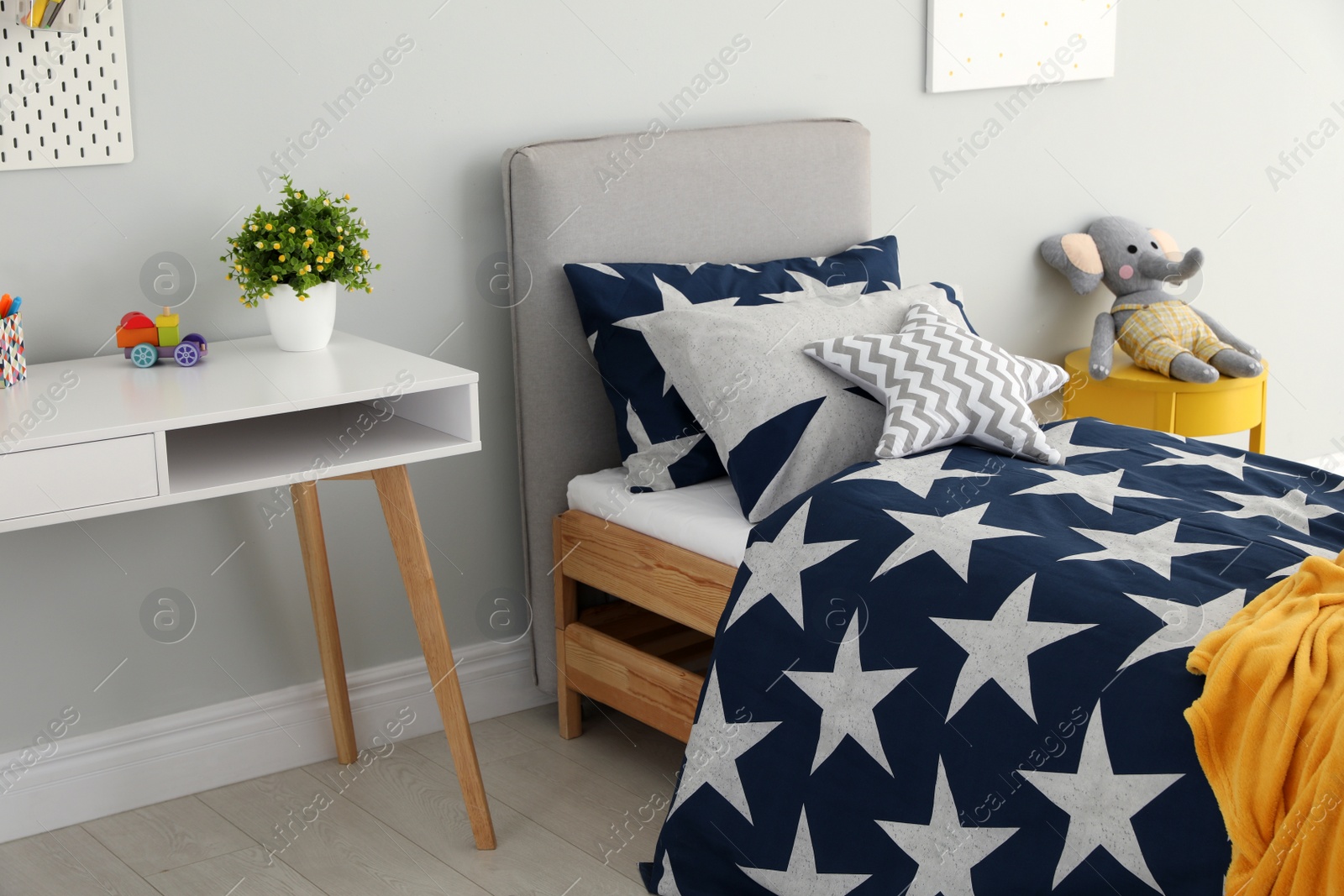 Bed with star patterned linens in child's bedroom. Interior design Photo of Bed with star patterned linens in child's bedroom. Interior design