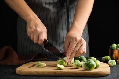 Woman cutting Brussels sprout at black slate table, closeup Photo of Woman cutting Brussels sprout at black slate table, closeup