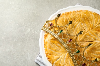 Traditional galette des Rois with decorative crown on light grey table, flat lay. Space for text Photo of Traditional galette des Rois with decorative crown on light grey table, flat lay. Space for text