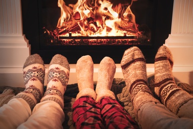 Lovely family in warm socks resting near fireplace at home, closeup Photo of Lovely family in warm socks resting near fireplace at home, closeup