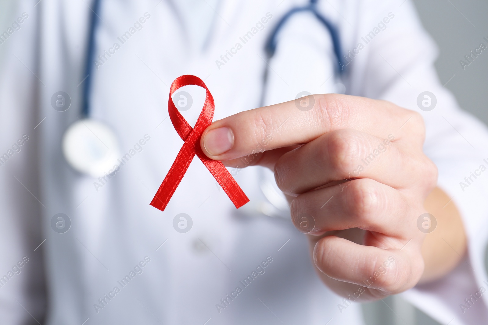Doctor holding red awareness ribbon, closeup. World AIDS disease day Photo of Doctor holding red awareness ribbon, closeup. World AIDS disease day