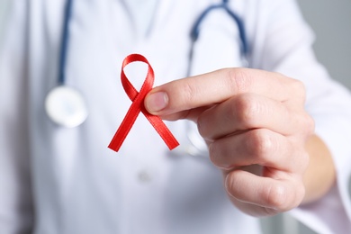Doctor holding red awareness ribbon, closeup. World AIDS disease day Photo of Doctor holding red awareness ribbon, closeup. World AIDS disease day