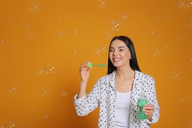 Young woman blowing soap bubbles on yellow background Photo of Young woman blowing soap bubbles on yellow background