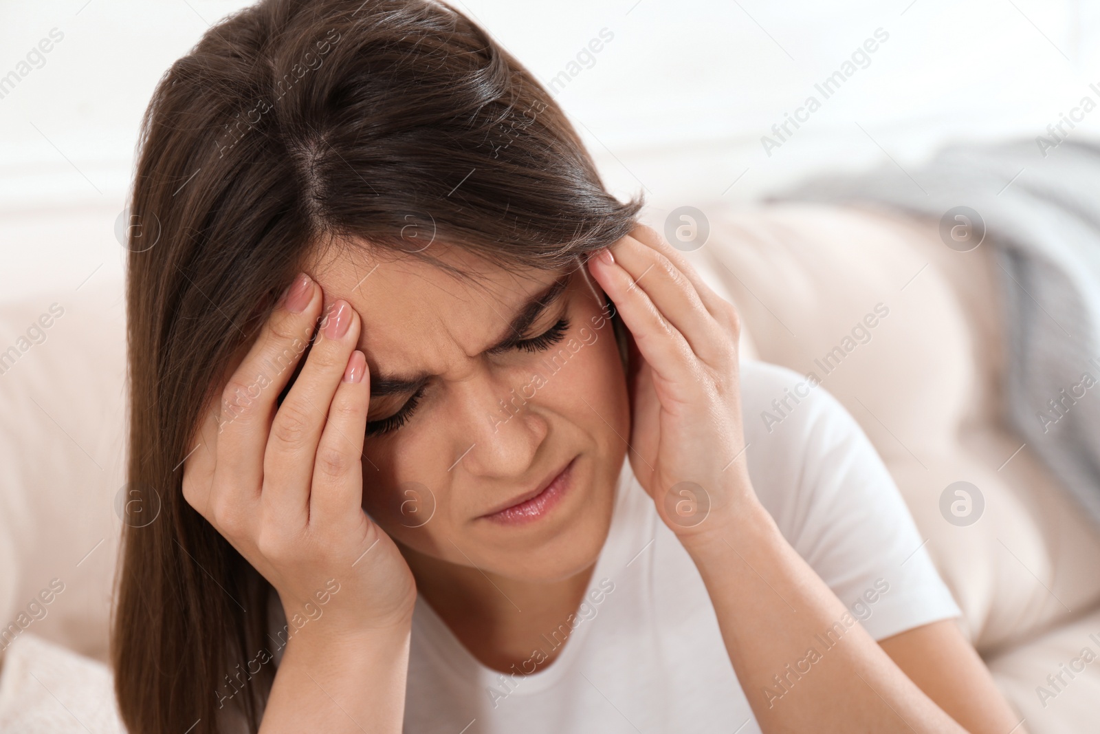 Young woman suffering from migraine on sofa at home Photo of Young woman suffering from migraine on sofa at home