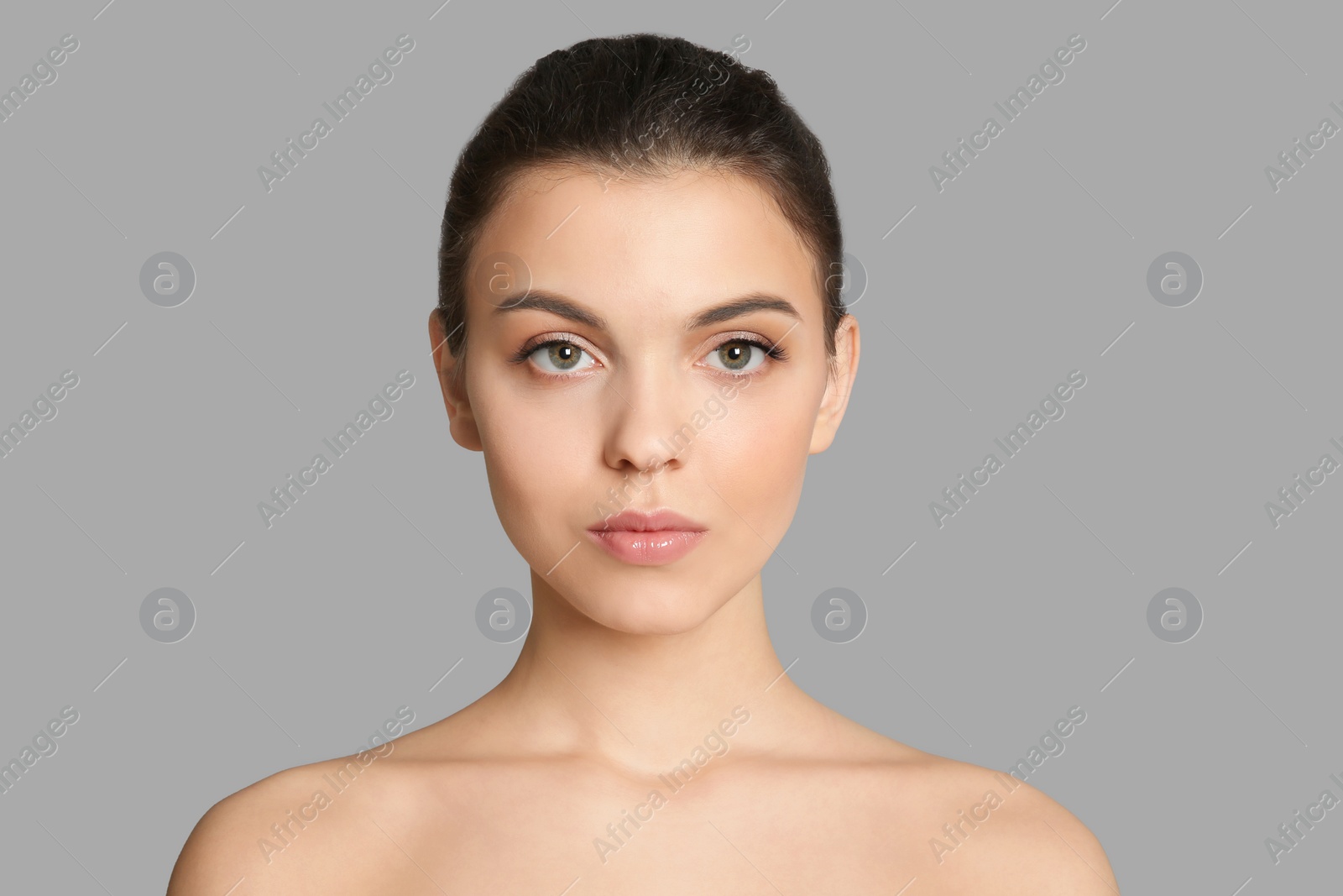 Photo of Young woman with beautiful makeup on grey background. Professional cosmetic products