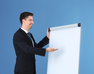 Business trainer giving presentation on flip chart board against color background Photo of Business trainer giving presentation on flip chart board against color background