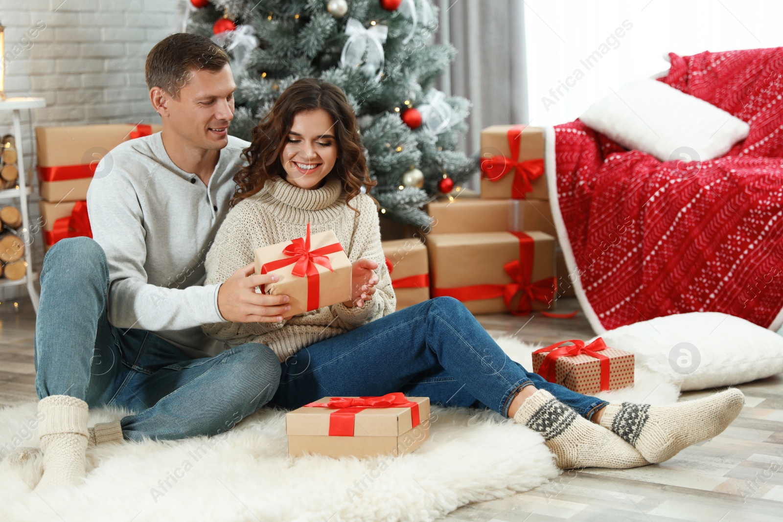 Man presenting Christmas gift to his girlfriend at home Image of Man presenting Christmas gift to his girlfriend at home