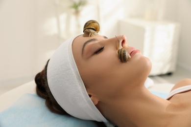 Young woman receiving snail facial massage in spa salon Photo of Young woman receiving snail facial massage in spa salon