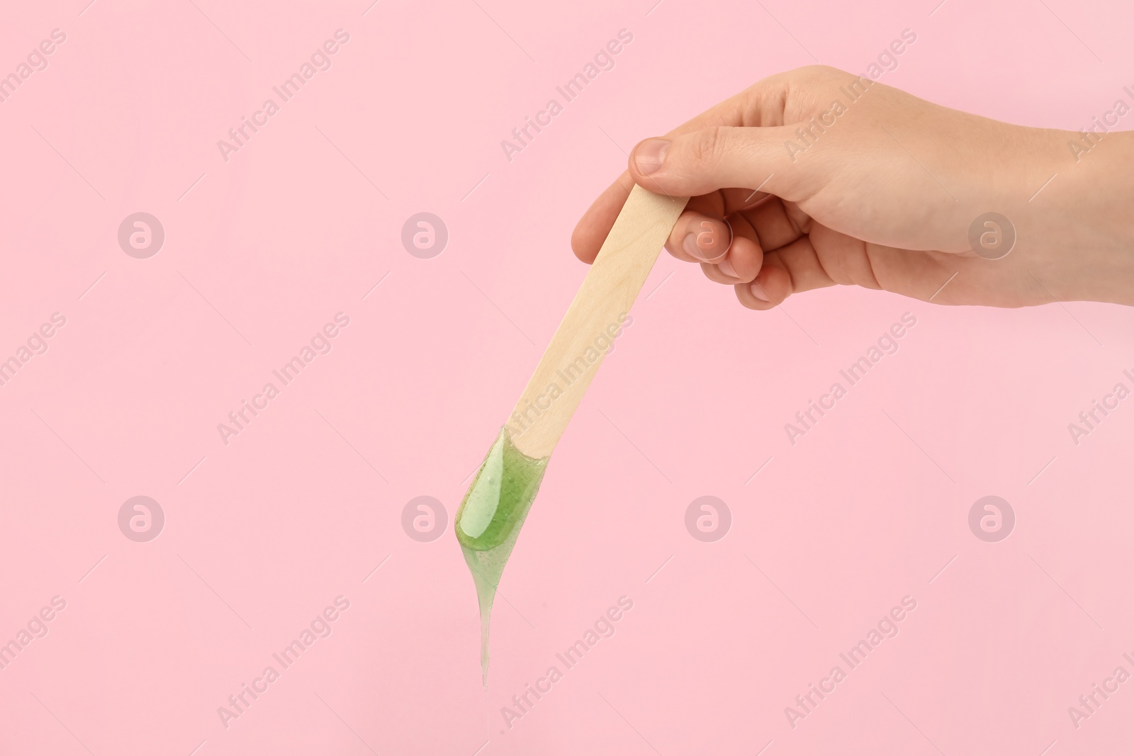 Woman holding spatula with hot depilatory wax on pink background, closeup Photo of Woman holding spatula with hot depilatory wax on pink background, closeup