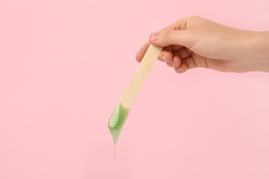 Woman holding spatula with hot depilatory wax on pink background, closeup Photo of Woman holding spatula with hot depilatory wax on pink background, closeup