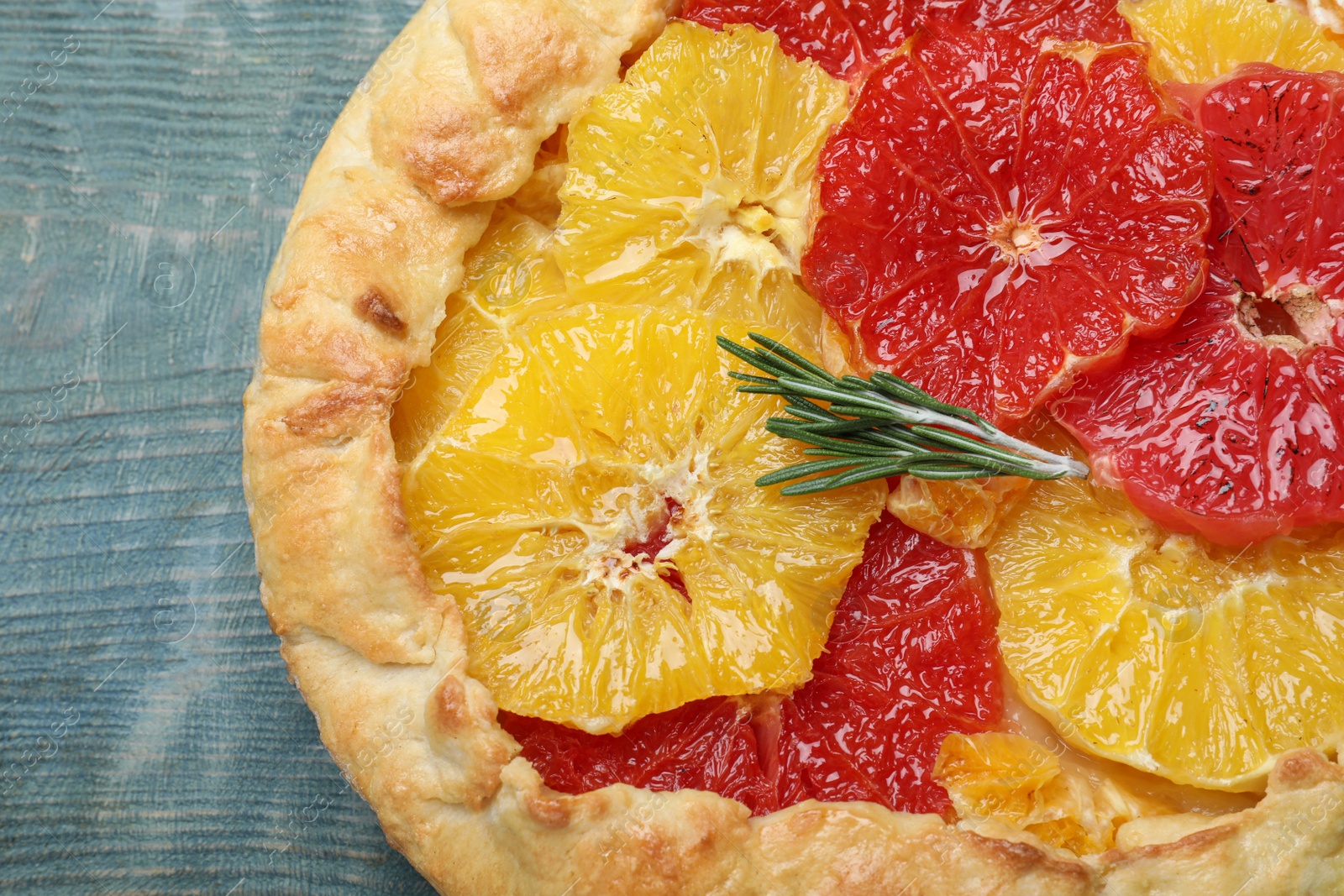 Delicious galette with citrus fruits and rosemary on blue wooden table, top view Photo of Delicious galette with citrus fruits and rosemary on blue wooden table, top view