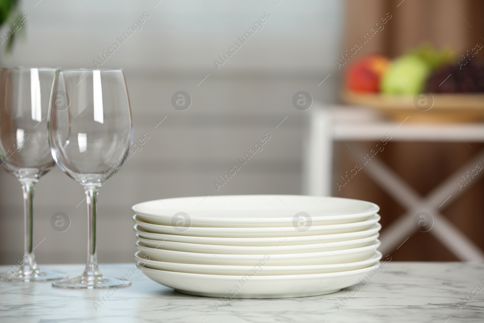 Stack of plates and glasses on white marble table indoors Photo of Stack of plates and glasses on white marble table indoors