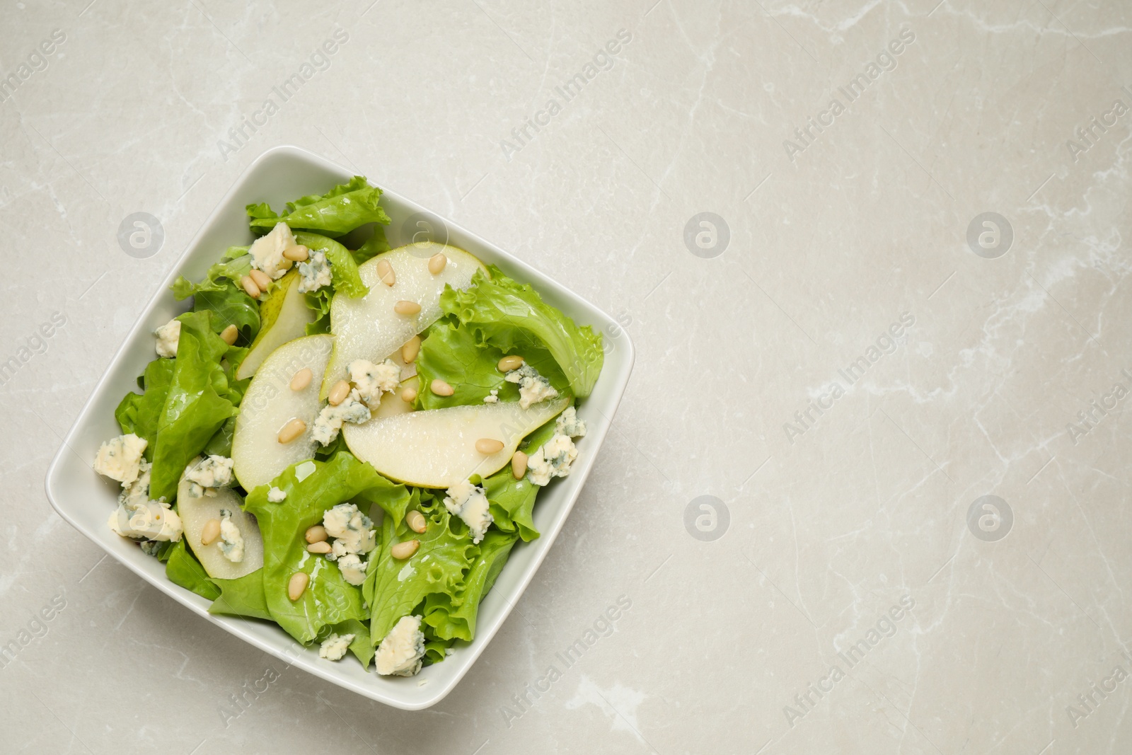 Fresh salad with pear on light table, top view. Space for text Photo of Fresh salad with pear on light table, top view. Space for text