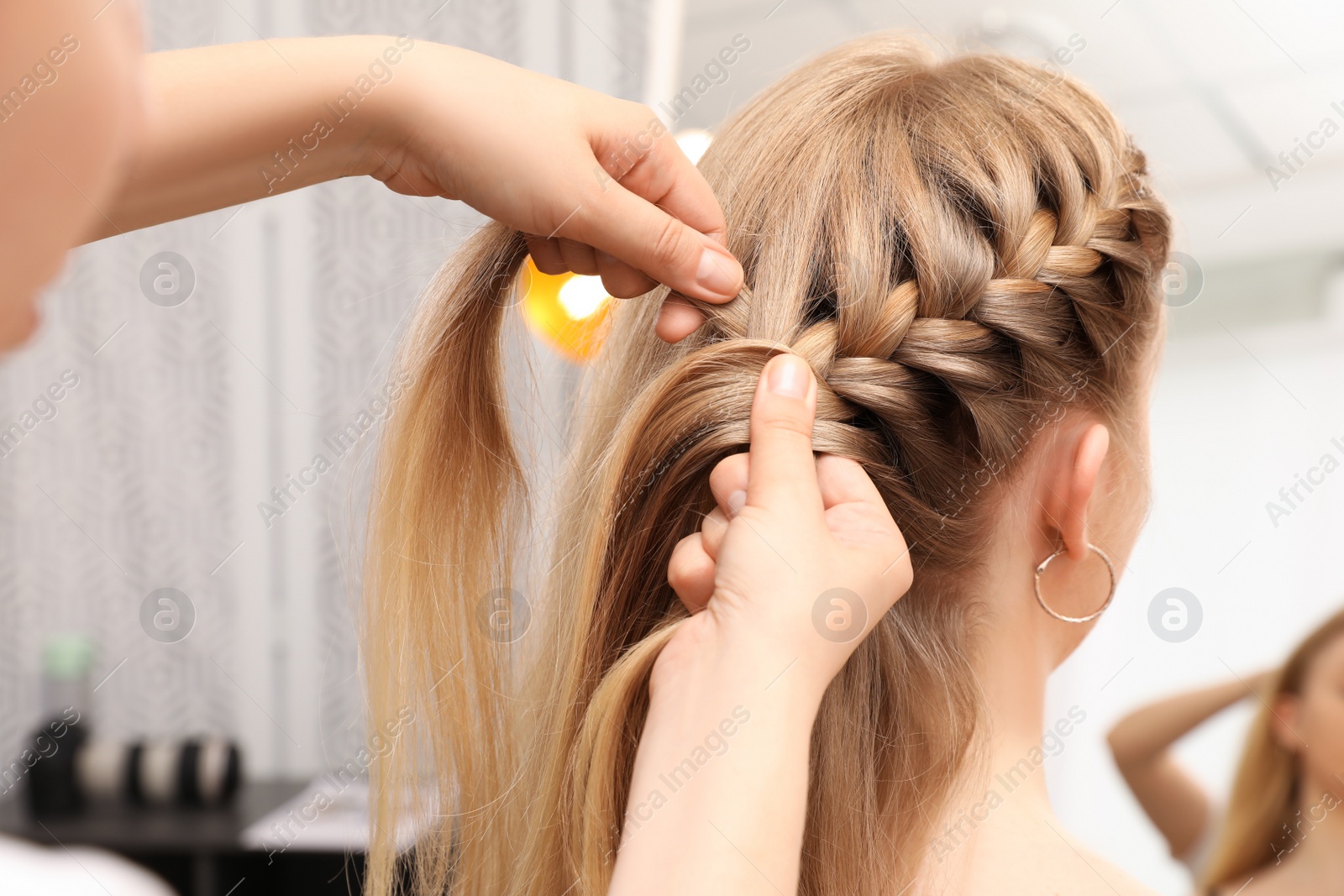Professional stylist braiding client's hair in salon Photo of Professional stylist braiding client's hair in salon