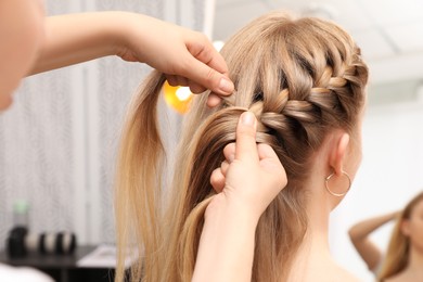 Professional stylist braiding client's hair in salon Photo of Professional stylist braiding client's hair in salon