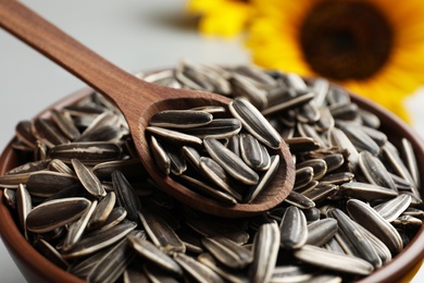 Raw sunflower seeds and wooden spoon in bowl, closeup Photo of Raw sunflower seeds and wooden spoon in bowl, closeup