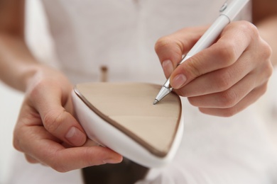 Young bride writing on her shoe indoors, closeup. Wedding superstition Photo of Young bride writing on her shoe indoors, closeup. Wedding superstition