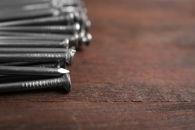 Photo of Many metal nails on wooden background, closeup. Space for text